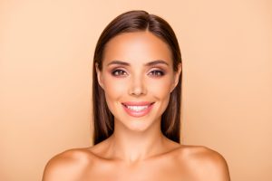 Close up picture photo of lovely charming pretty brown-haired lady with her naked shoulders she isolated on pastel beige background make white beaming big smile