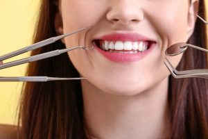 Beautiful smiling young woman with dental tools, closeup