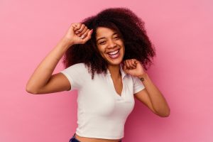 Young african american woman isolated on pink background dancing and having fun.