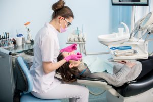 Female dentist with dental tools - mirror and probe checking up patient teeth at dental clinic office. Medicine, dentistry and health care concept. Dental equipment