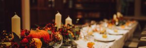 Thanksgiving table setting with automnal decorations, pumpkins, glasses and plates. Holidays, catering and hospitality concept.