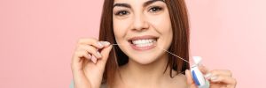 Young woman flossing teeth on color background