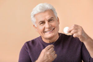 Senior man flossing teeth on color background