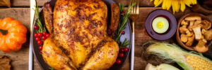 Cooked chicken for Thanksgiving Day. Baked whole chicken or turkey with autumn vegetables, mushrooms and berries for festive dinner on wooden table. Thanksgiving Day, holidays concept. Top view
