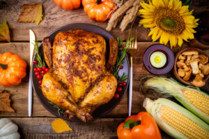Cooked chicken for Thanksgiving Day. Baked whole chicken or turkey with autumn vegetables, mushrooms and berries for festive dinner on wooden table. Thanksgiving Day, holidays concept. Top view