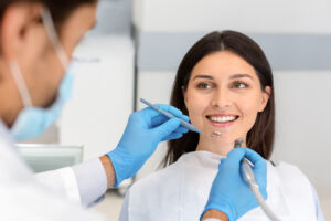 Smiling pretty woman looking at dentist with trust, doctor holding drilling tools, trust and care concept
