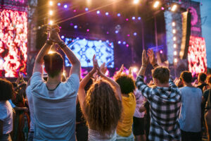 Rear view of group of unrecognizable young friends dancing at summer festival.