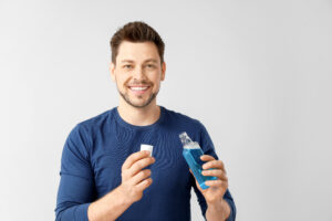 Man with mouth rinse on light background