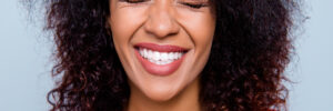 Closeup cropped portrait of funny comic woman with clenched white healthy teeth close eyes making a wish isolated on grey background. Toothcare tooth care treatment therapy concept