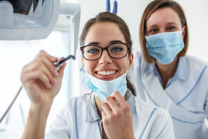 Two female dentist in dental office examining patient teeth.Came