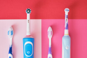 different toothbrushes on pink and red background, electric toothbrushes or plastic toothbrushes, environmental friendliness lifestyle concept, efficiency of brushing teeth