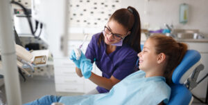 Young female dentist show jaw to little girl