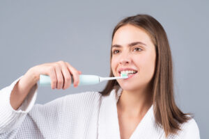 Young woman brushing teeth. Beautiful smile of young woman with healthy white teeth. Isolated background. Dental care. White tooth