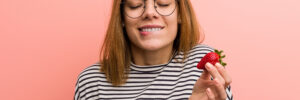 Portrait of young woman tasting a fresh strawberry