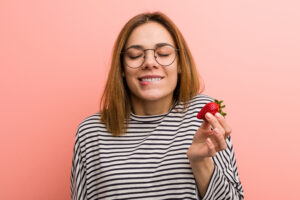 Portrait of young woman tasting a fresh strawberry