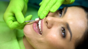 Stomatologist comparing color of natural tooth with sealant filling, closeup