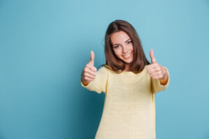 Beautiful smiling young woman giving thumbs up isolated on the blue background